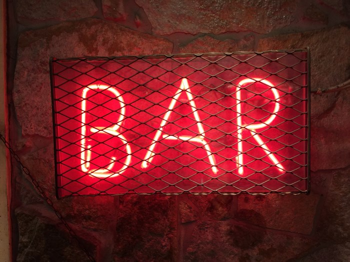 Red neon BAR sign on a stone wall