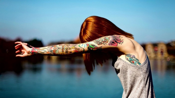 Woman with full arm tattoo by water