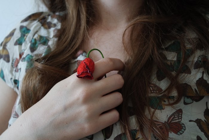 Woman with a red poppy ring on her finger