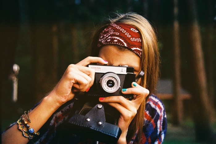 Woman with vintage camera and bandana taking a photo