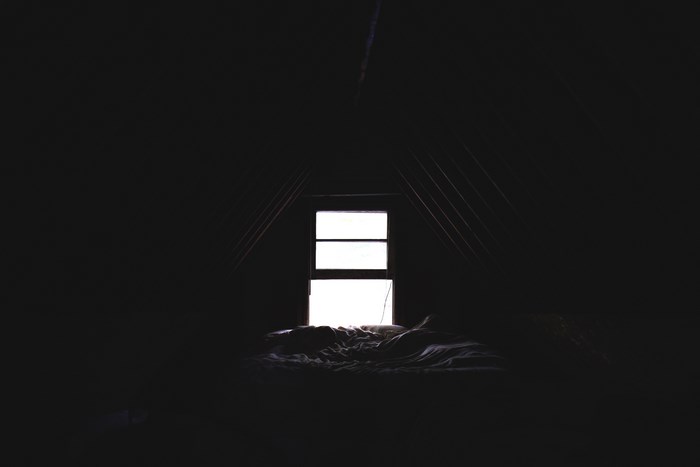 Dark room with a bed and window