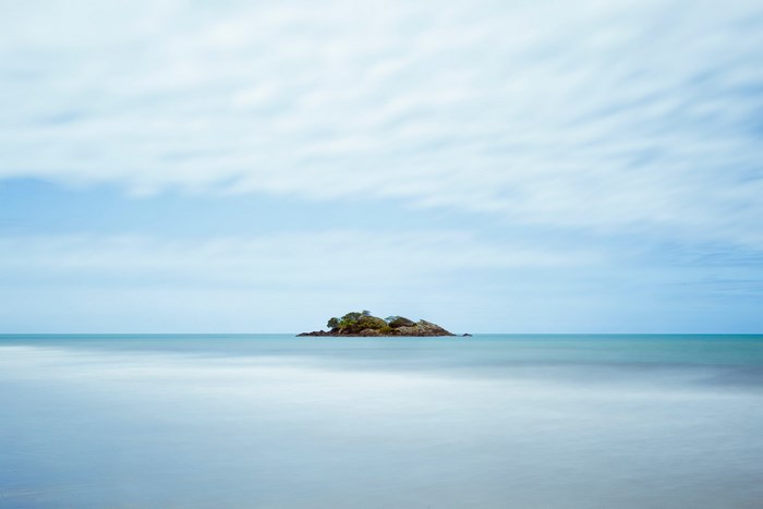 Small island in the ocean with cloudy sky