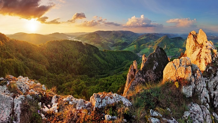 Sunrise over forested mountains and rocky peaks