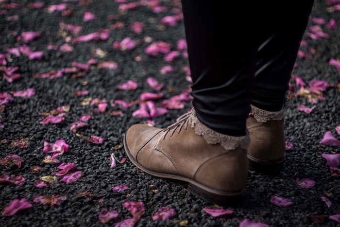Person in brown boots walking on pink flower petals