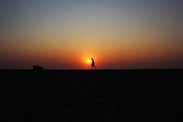 Silhouette of a man walking on a beach at sunset