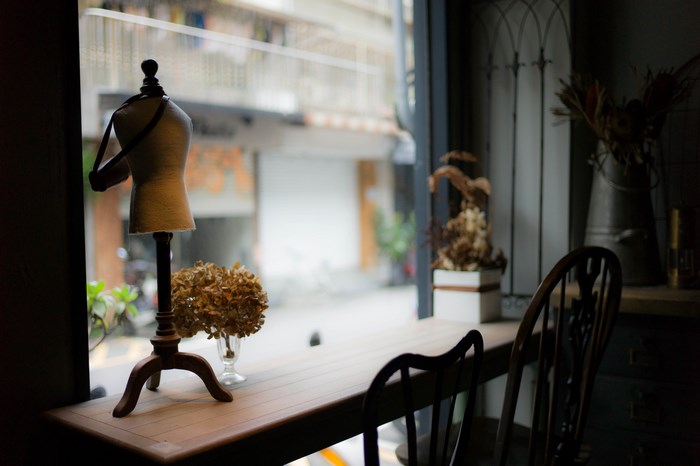 Miniature dress form and dried flowers on a table by the window