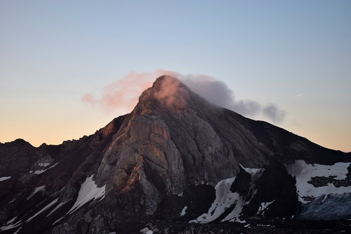 Mountain peak at sunrise with clouds and snow