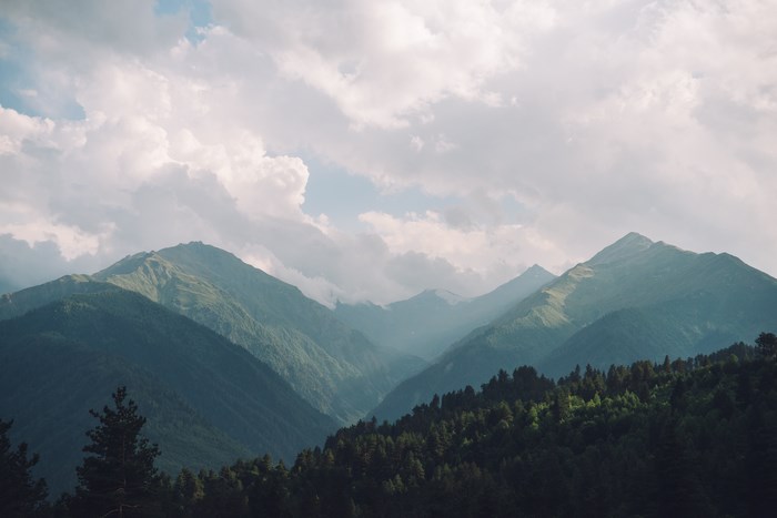 Mountain range with green slopes and cloudy sky