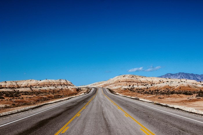 Desert highway with rolling hills under a clear blue sky