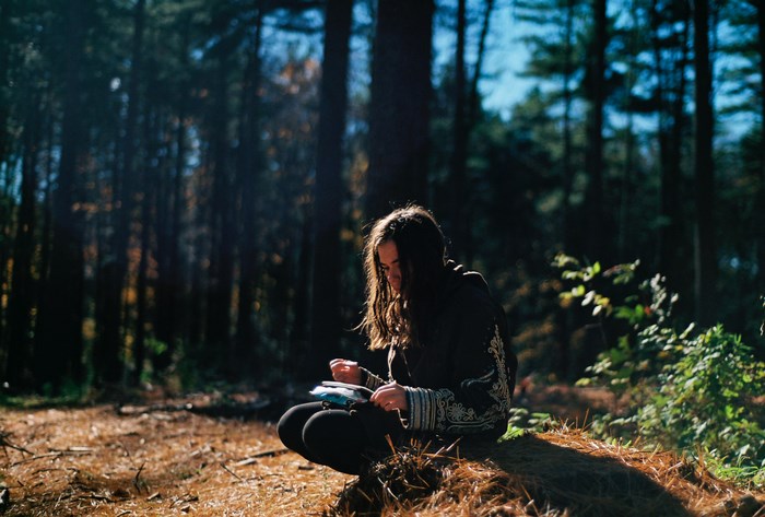 Girl journaling in a sunlit forest