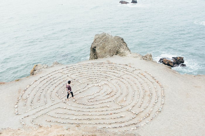 Person walking through a stone maze on a cliff overlooking the ocean