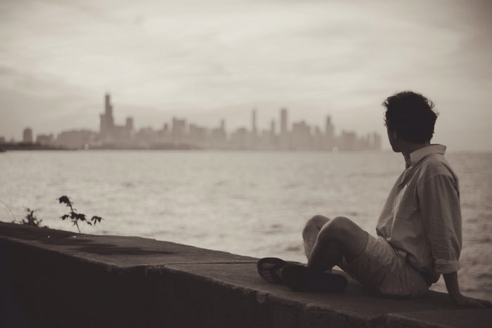 Man sitting on a ledge overlooking a city skyline