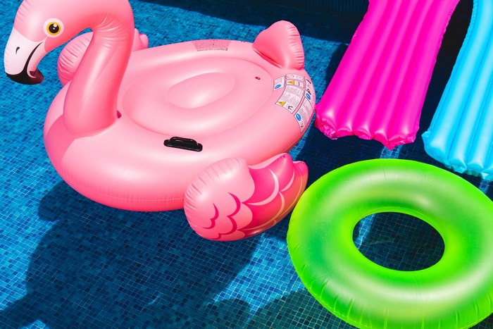 Pink flamingo float and colorful rings in a pool