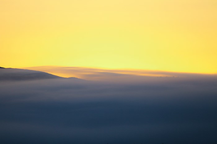 Mountain range covered in fog under a yellow sky