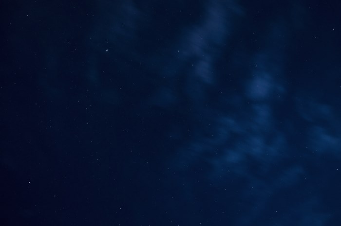 Starry night sky with clouds and distant stars