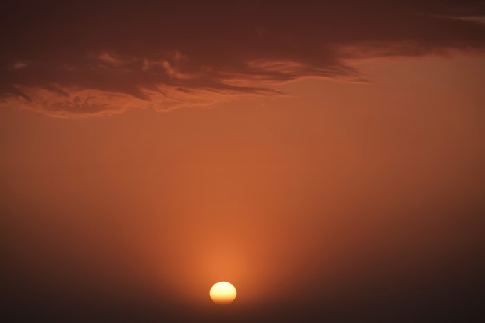 Sunset over a hazy orange sky with clouds