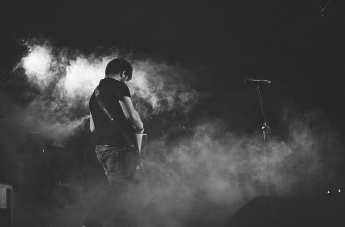 Man playing guitar on stage with smoke