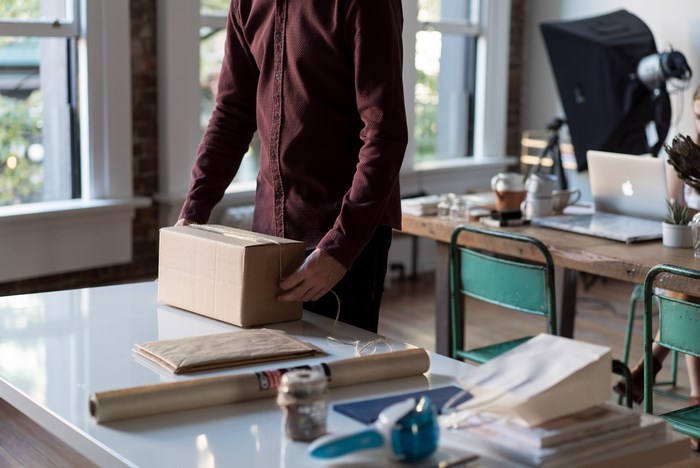 Man packing a cardboard box on a white worktop