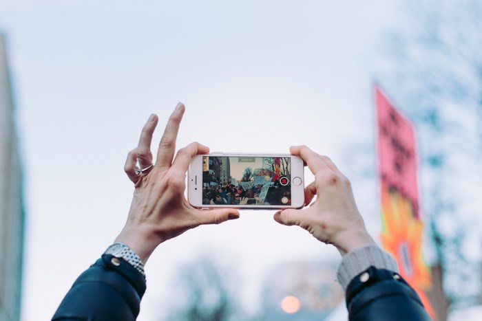 Woman filming a protest with an iPhone