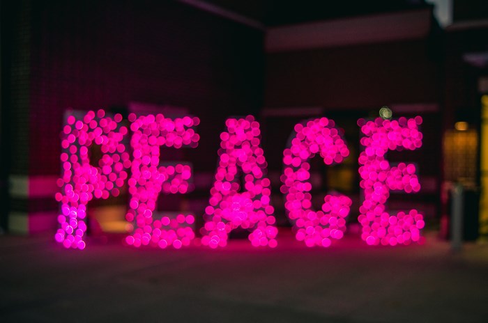 Pink neon lights spell out the word PEACE