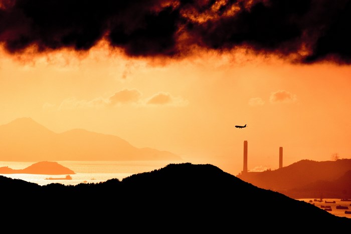 Silhouette of airplane flying over mountains at sunset