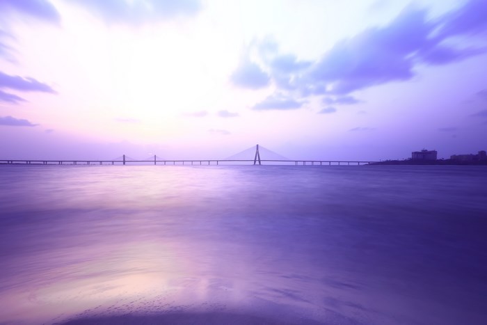 Purple sunset over a long bridge and calm water