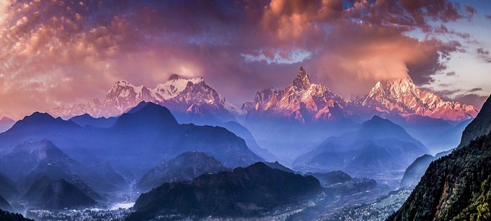 Himalayan mountain range at sunset with clouds and mist