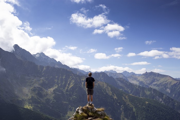 Man standing on a mountain peak overlooking Tatra range