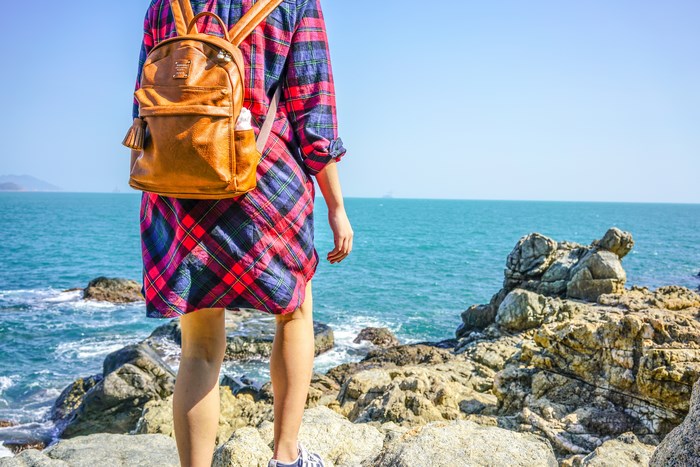 Woman with backpack on rocky coast overlooking the ocean