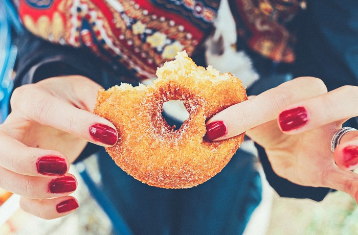 Woman holding a bitten cinnamon sugar donut