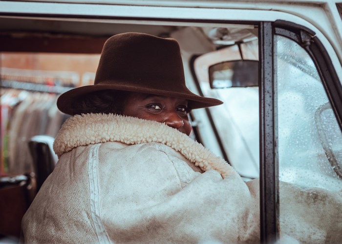 Woman in a hat and coat driving a van