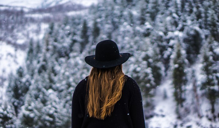 Woman in Black Hat Overlooking Snowy Forest