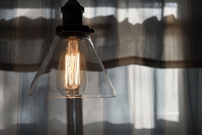 Close-up of a glowing Edison light bulb in a glass lampshade