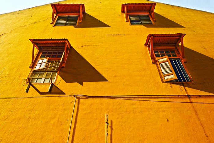 Yellow building with open windows and shadows