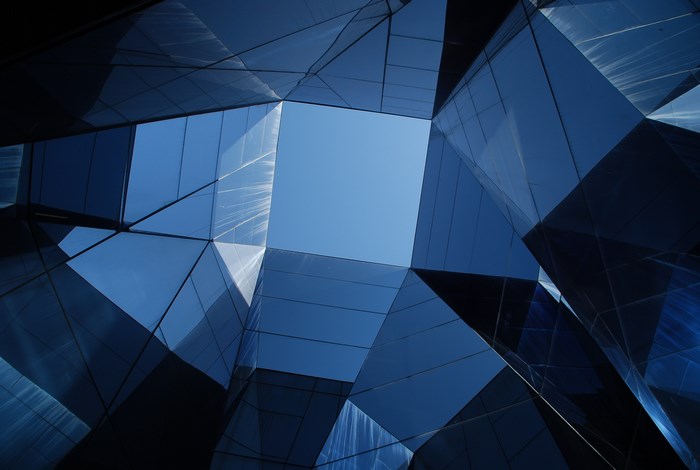 Geometric glass building reflecting blue sky