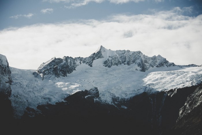 Snow-covered mountain range with glacier and clouds
