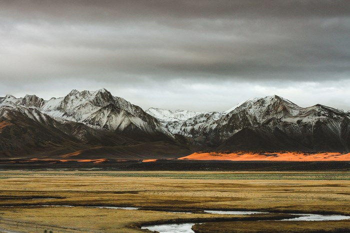 Snow-capped mountains under a cloudy sky with a river