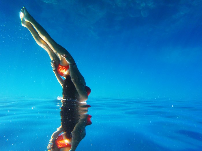Woman in orange swimsuit diving underwater
