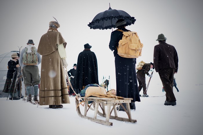 People in vintage winter clothing with sled and skis in snow
