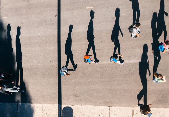 People walking on a street casting long shadows