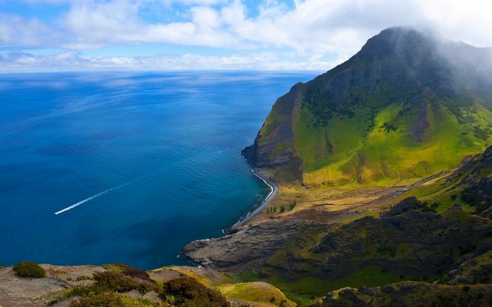 Coastal mountain landscape with a boat on the sea