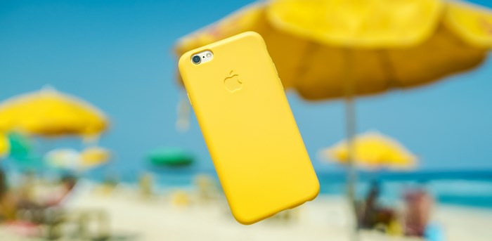 Yellow iPhone levitating on a beach with umbrellas