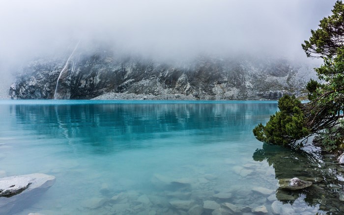 Turquoise lake in Peru with misty mountains and rocks