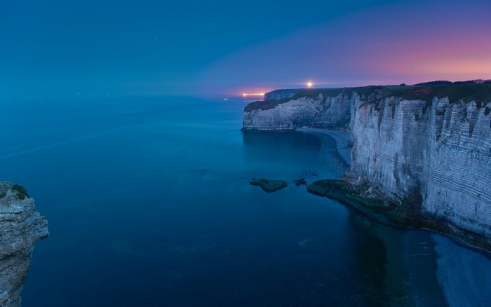 Cliff coast at dusk with ocean and distant lights