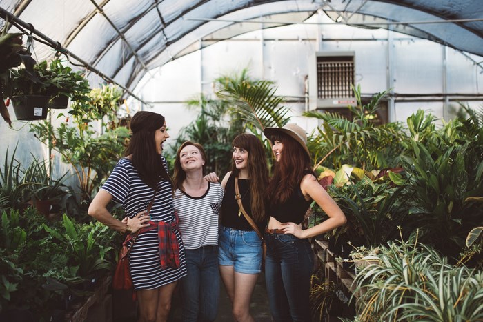 Four women standing in a greenhouse with plants