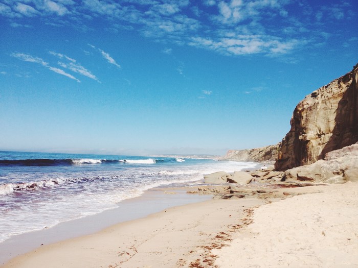 Beach with waves crashing against a cliff