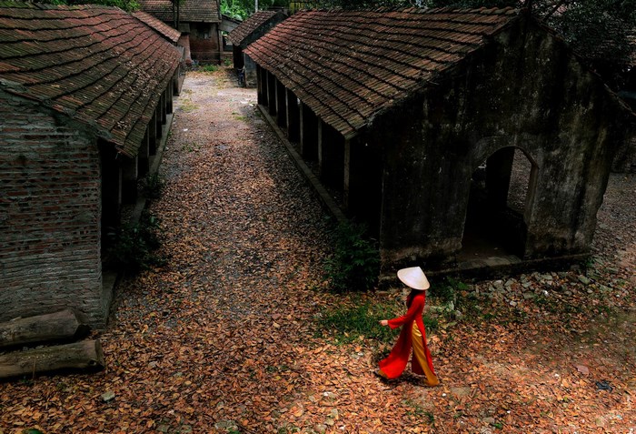 Woman in traditional Vietnamese dress walks through old village
