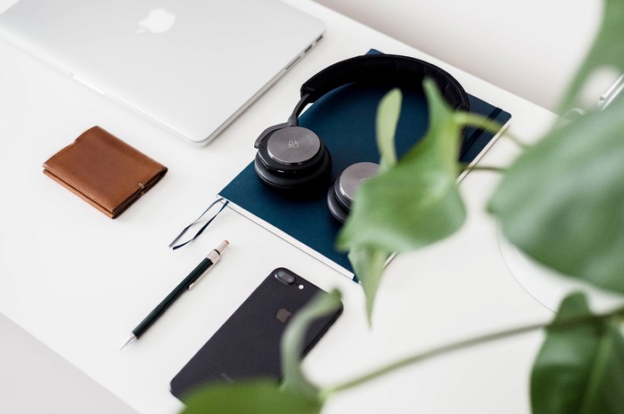 Apple Laptop, Headphones, Wallet, Phone, and Plant on Desk