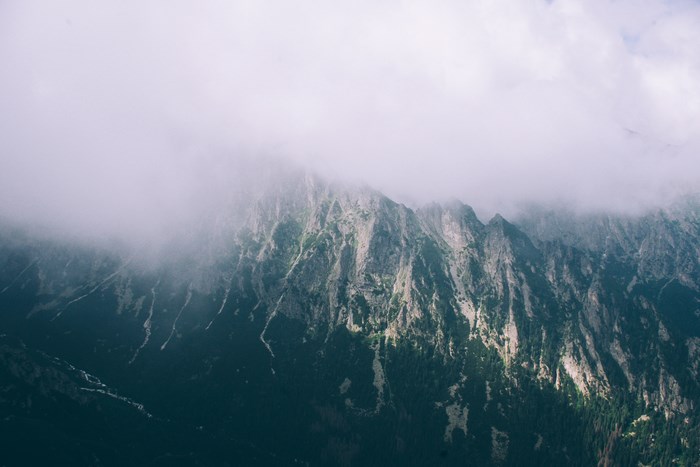 Misty mountain range with trees and clouds