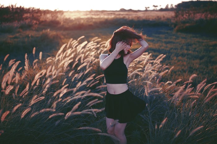 Woman dancing in tall grass during golden hour